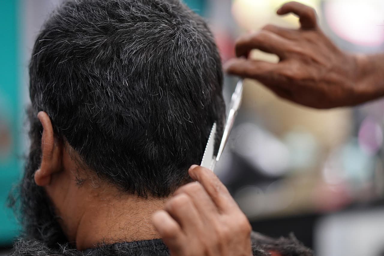 Barber trimming around the ear on a man with a full beard