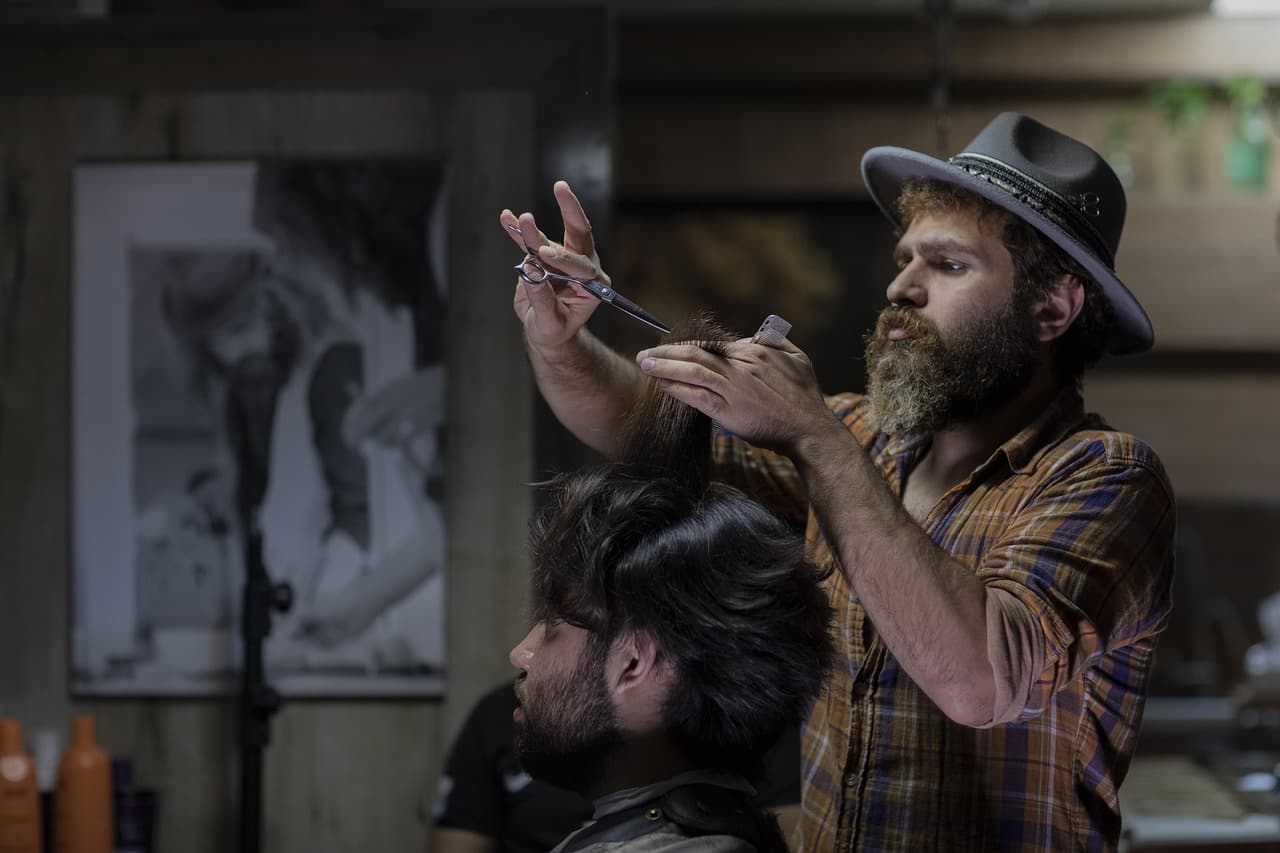 Barber shaping a customer's cut with scissors and comb